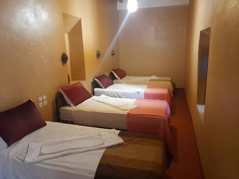 Quadruple Room: four single beds in a row, with striped blankets