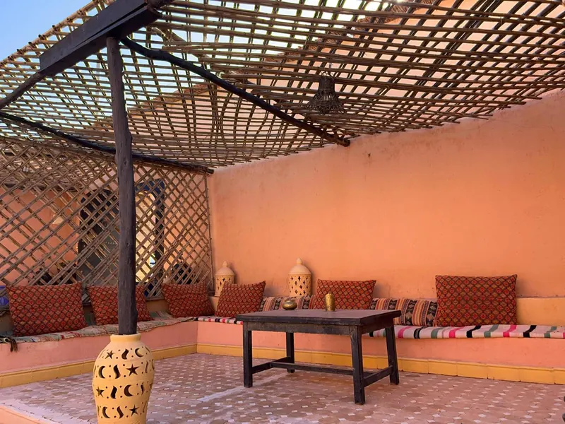 The shaded terrace under a wooden pergola, with cushions along the walls